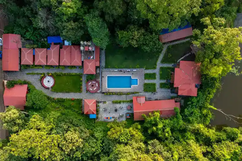 Wide drone shot of Wild Wings Dandeli resort campus with pool and cottages