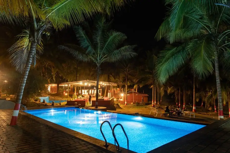 Night view of Dandeli Safar resort swimming pool with warm ambient lighting